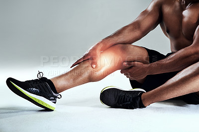 Buy stock photo Cropped shot of a sporty young man nursing a calf injury against a grey background