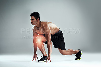 Buy stock photo Shot of a sporty young man on his mark with a knee injury against a grey background