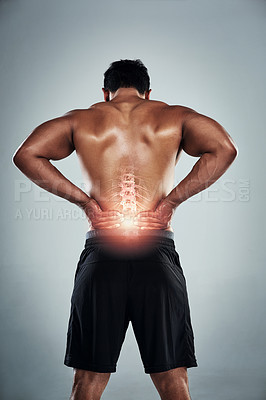 Buy stock photo Rearview shot of a sporty young man holding his back in pain against a grey background
