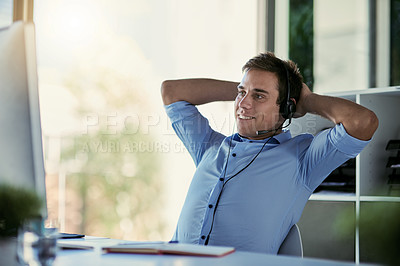 Buy stock photo Cropped shot of a call centre agent taking a break at his office desk