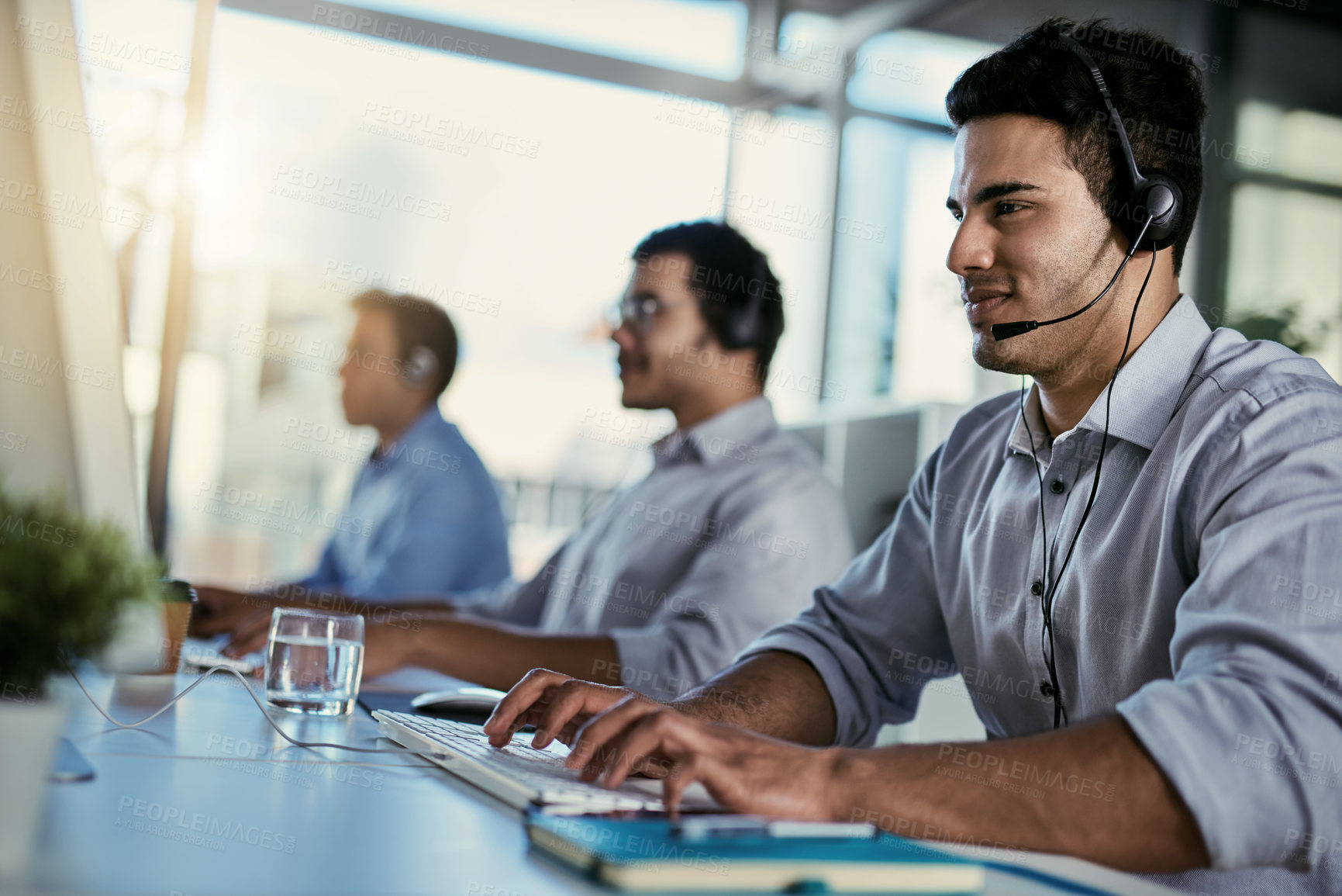 Buy stock photo Crm agent, smile and man in coworking space consulting with advice and happiness at help desk. Happy phone call, conversation and customer support consultant speaking on headset in callcenter office.