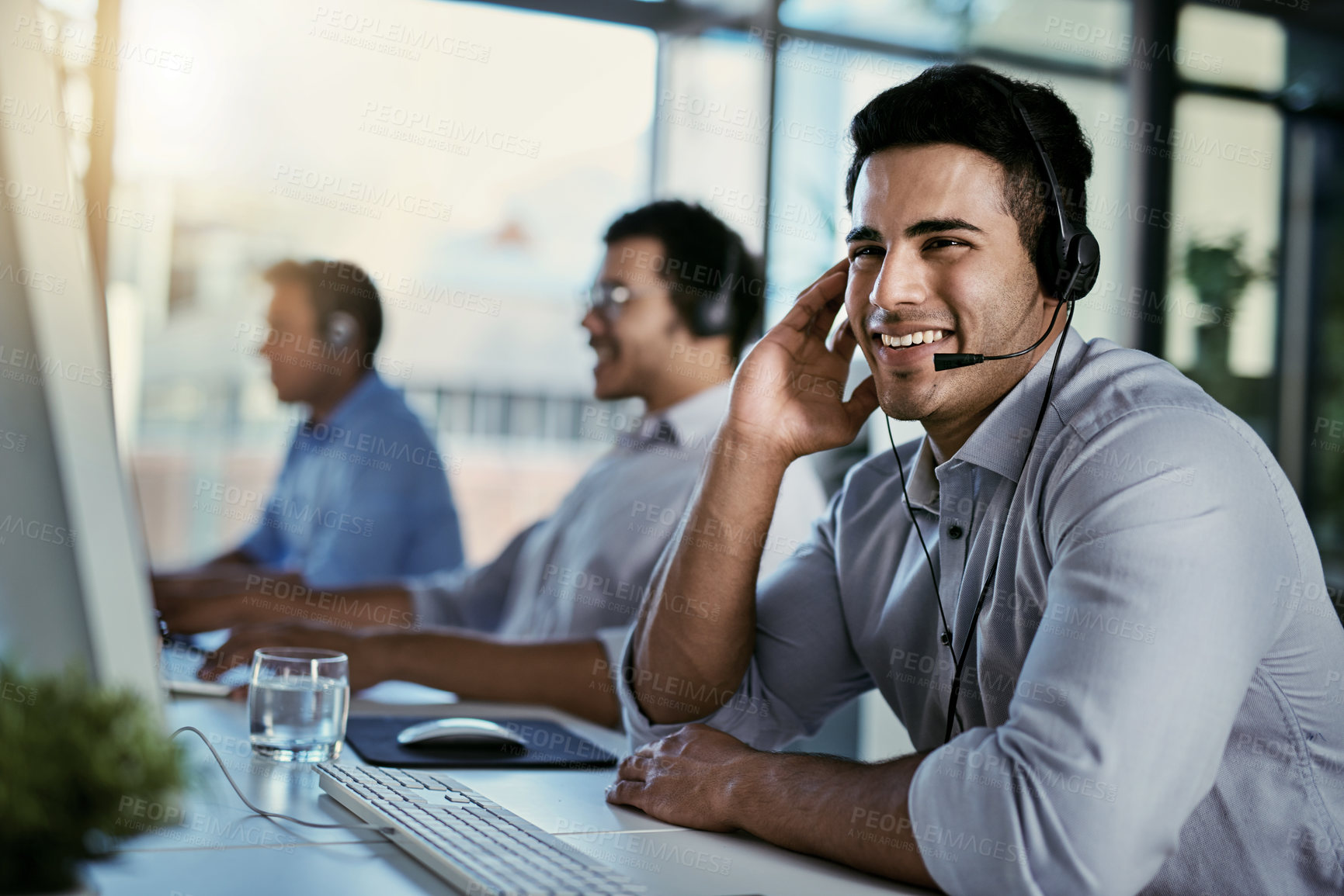Buy stock photo Callcenter agent, smile and man in office consulting with advice, help and happiness at desk. Happy phone call, conversation and service, customer support consultant speaking on headset at crm agency
