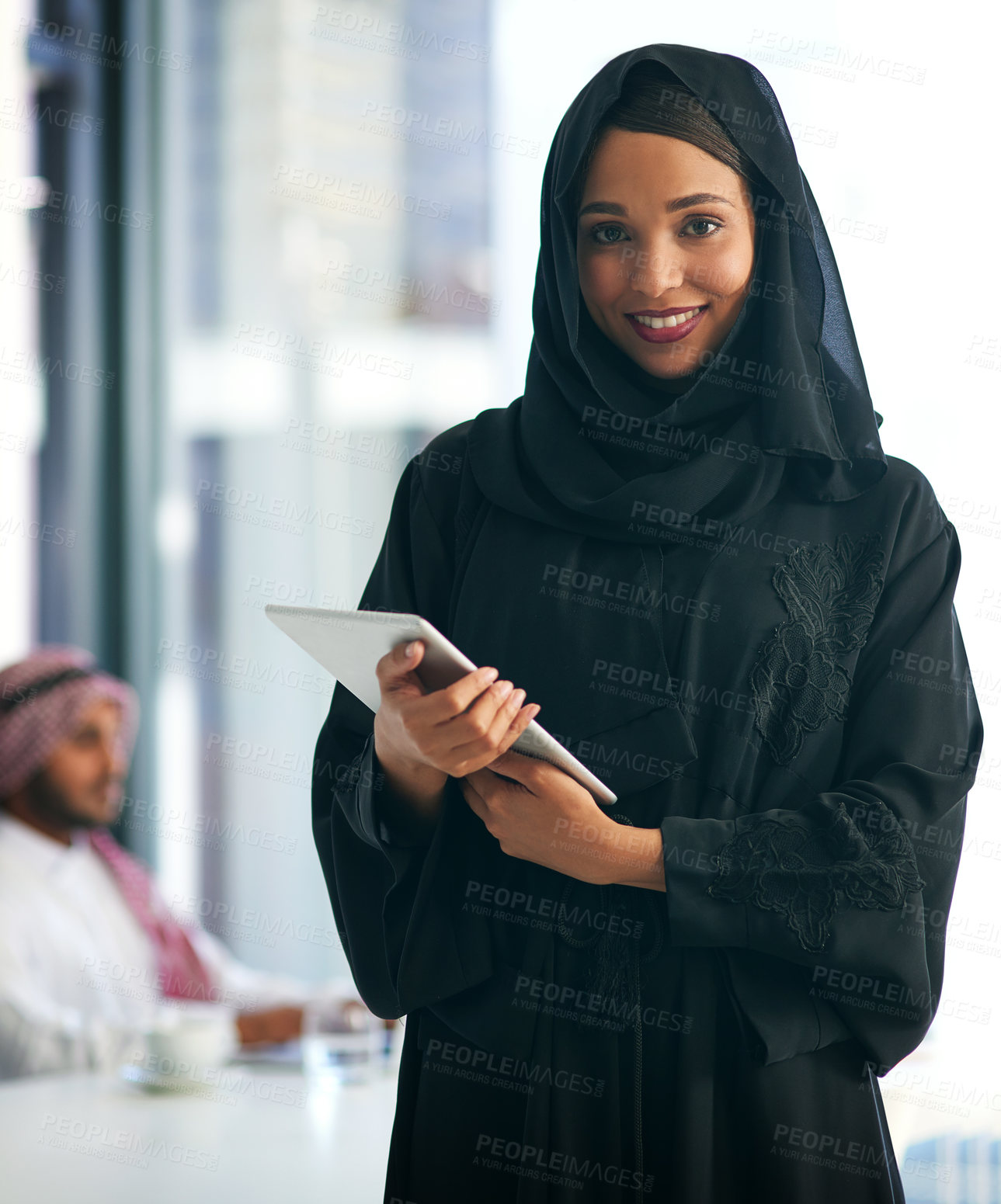 Buy stock photo Portrait of a young muslim businesswoman holding a digital tablet with her colleague working in the background