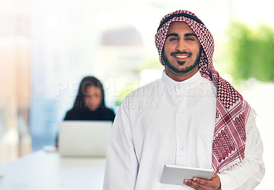 Buy stock photo Portrait of a young muslim businessman holding a digital tablet with her colleague working in the background