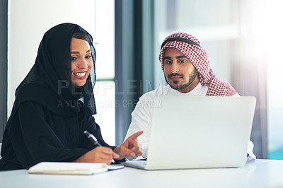 Buy stock photo Shot of two muslim coworkers using a laptop together in a modern office