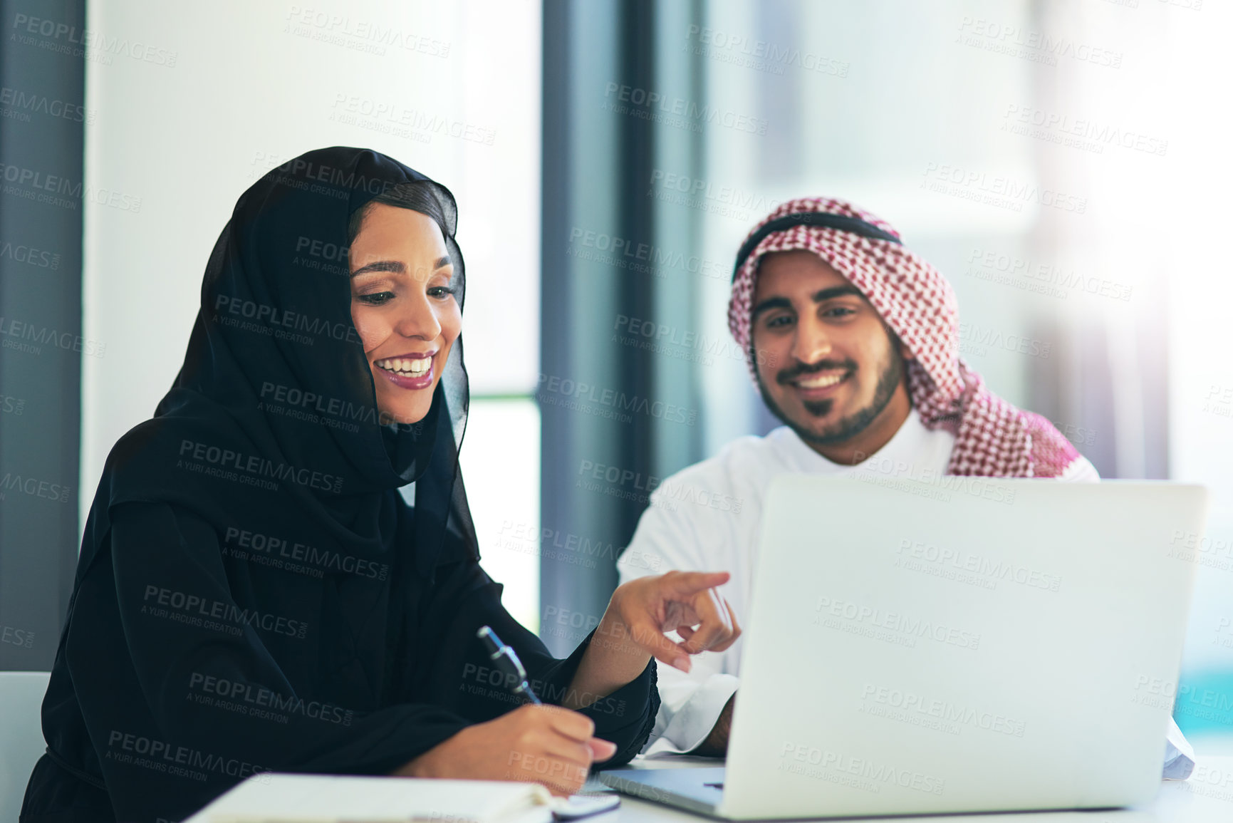 Buy stock photo Shot of two muslim coworkers using a laptop together in a modern office