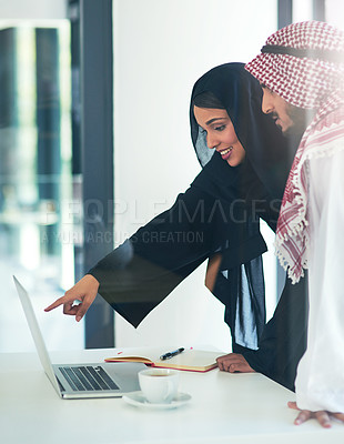 Buy stock photo Shot of two muslim coworkers using a laptop together in a modern office