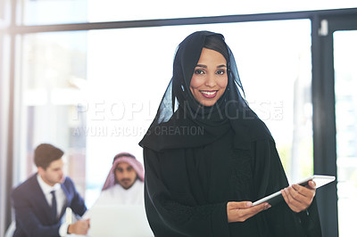 Buy stock photo Portrait of a young muslim businesswoman holding a digital tablet with her colleague working in the background