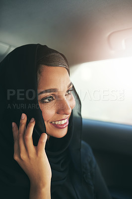 Buy stock photo Shot of a young muslim businesswoman using hers phone while traveling in a car