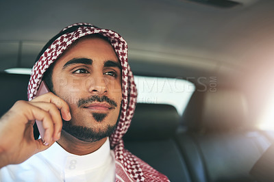 Buy stock photo Shot of a young muslim businessman using his phone while traveling in a car