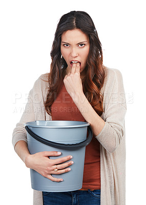 Buy stock photo Portrait of a young woman imitating nausea while holding a bucket in studio