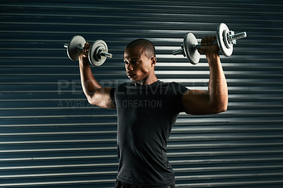 Buy stock photo Cropped shot of an athletic young man working out with dumbbells in the studio