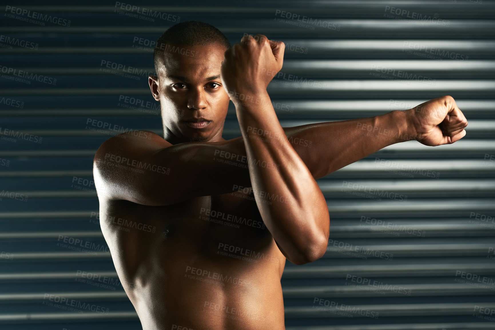 Buy stock photo Cropped portrait of an athletic young man going through his warmup routine in the studio