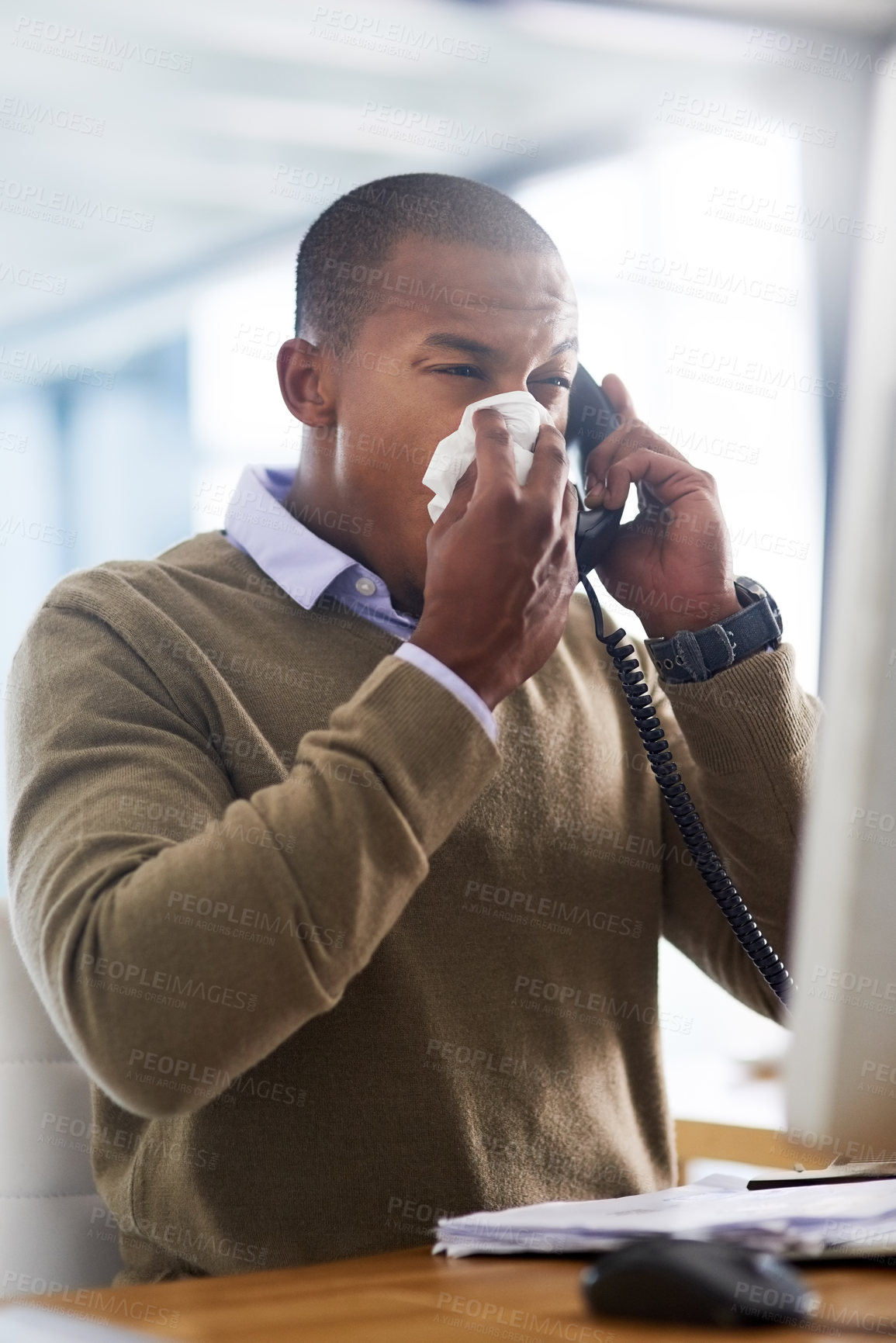 Buy stock photo Shot of a young businessman blowing his nose at his work desk