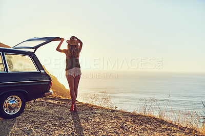Buy stock photo Rearview shot of a young woman standing next to her car during a roadtrip