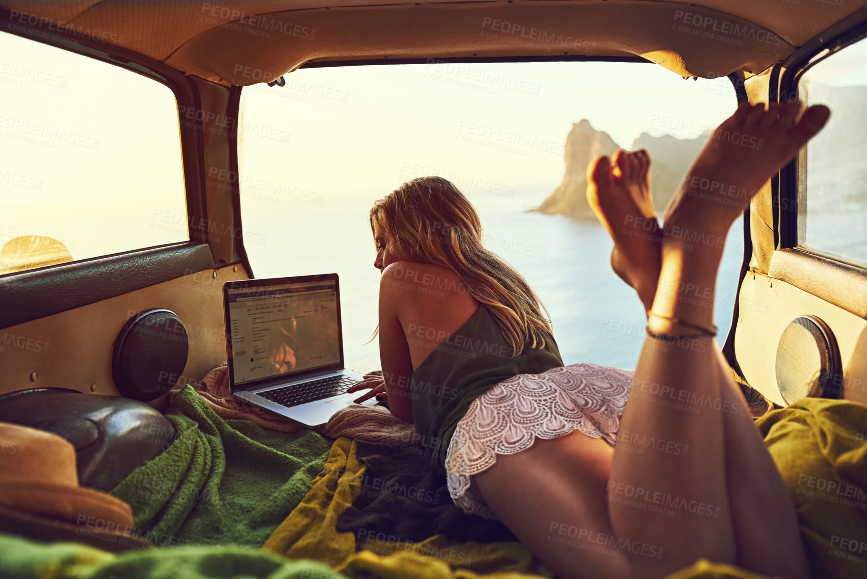Buy stock photo Shot of a young woman using her laptop while relaxing in the back of her car  on a roadtrip