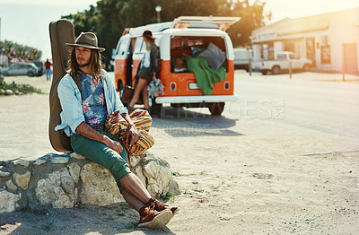 Buy stock photo Shot of a young man with a guitar on his back sitting at the side of the road with his girlfriend and van in the background