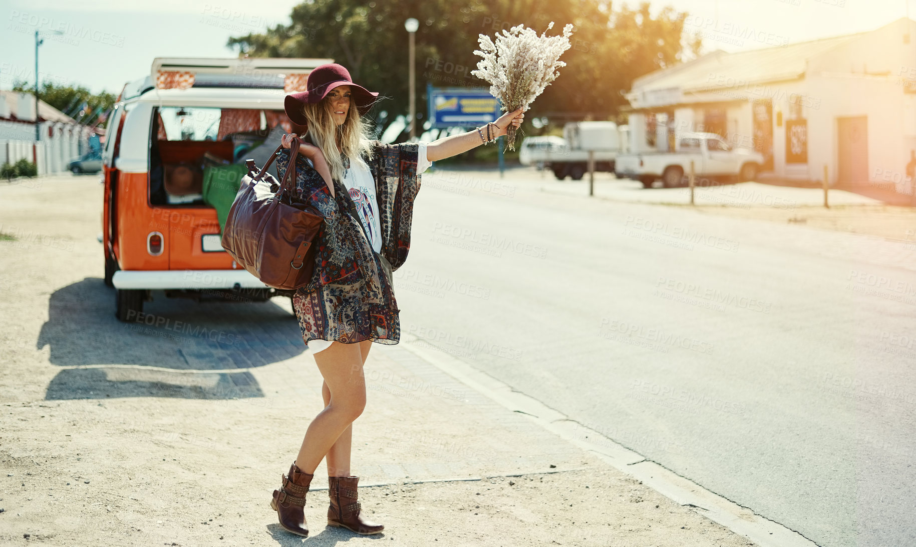 Buy stock photo Shot of a young hipster woman hitchhiking at the side of the road with her broken down van in the background