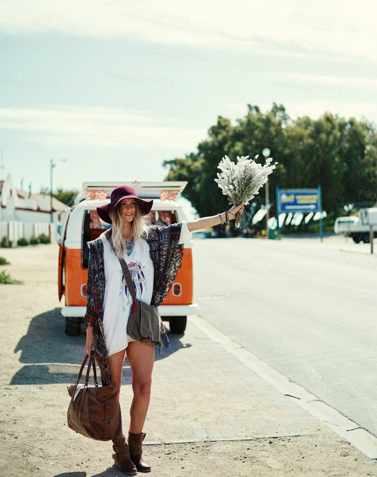 Buy stock photo Shot of a young hipster woman hitchhiking at the side of the road with her broken down van in the background