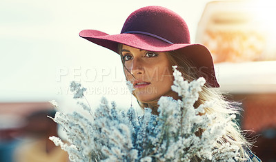 Buy stock photo Shot of a young woman standing outside with a bouquet of wildflowers