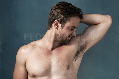 Buy stock photo Cropped shot of a handsome young man smelling his stinky armpits