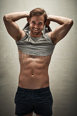 Buy stock photo Studio shot of a handsome and shirtless young man removing his vest to show off his six pack