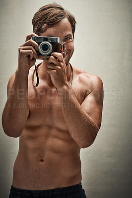 Buy stock photo Studio shot of a shirtless young man taking photos with a vintage camera