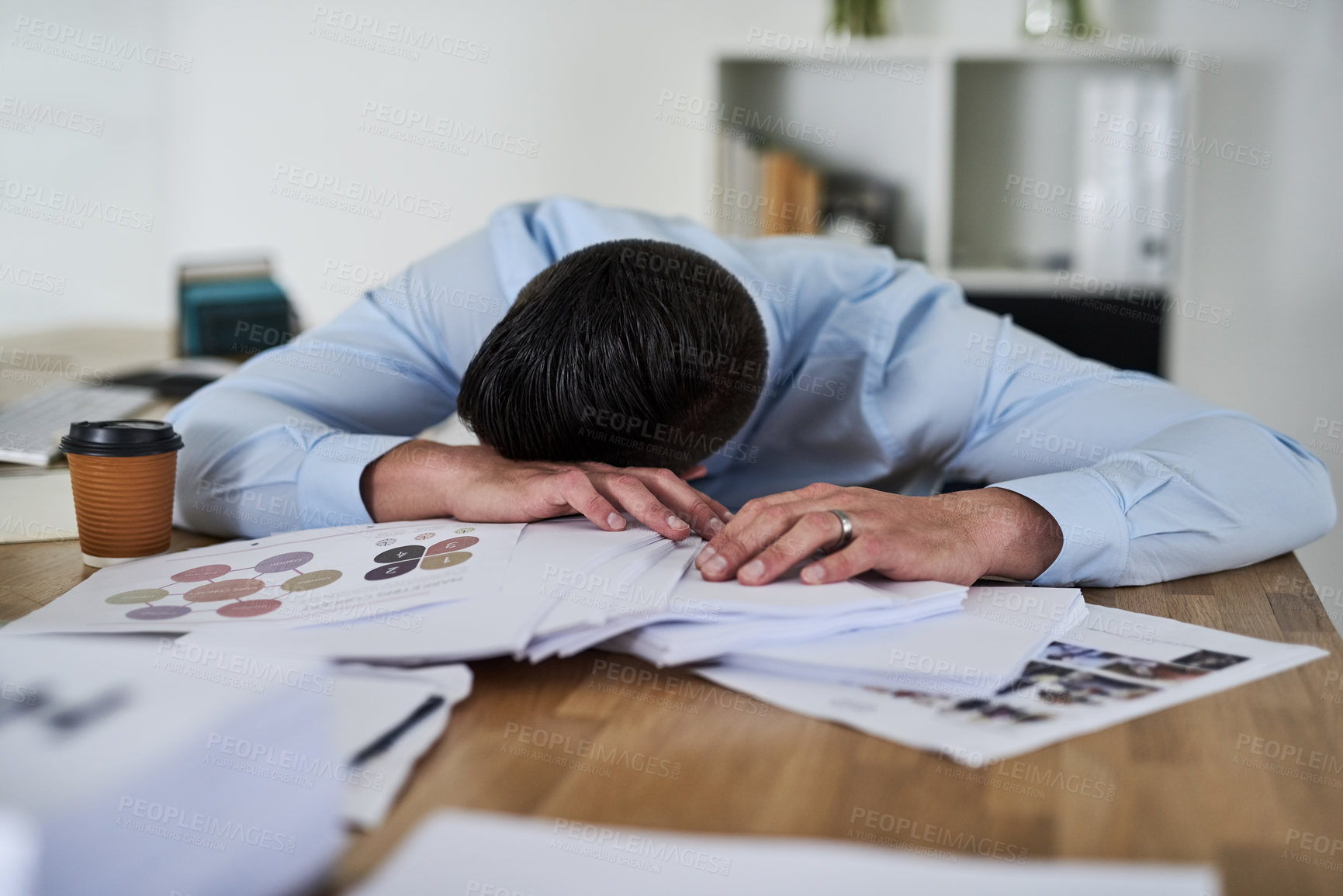 Buy stock photo Shot of a tired young businessman with his head down on a pile of paperwork in an office