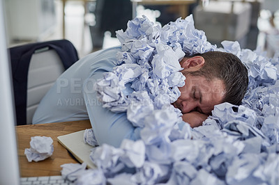 Buy stock photo Shot of a young businessman surrounded by piles of paper in an office