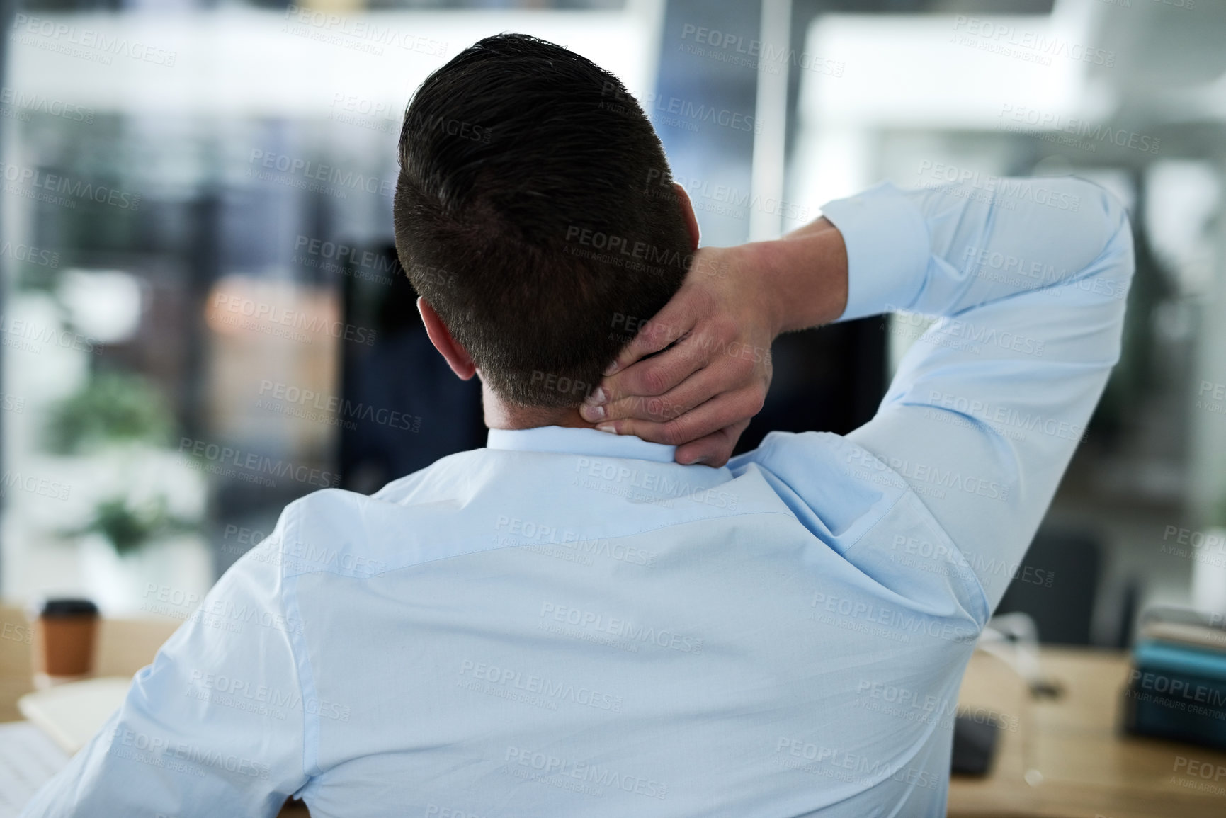 Buy stock photo Rearview shot of a young businessman experiencing neck pain while working in an office
