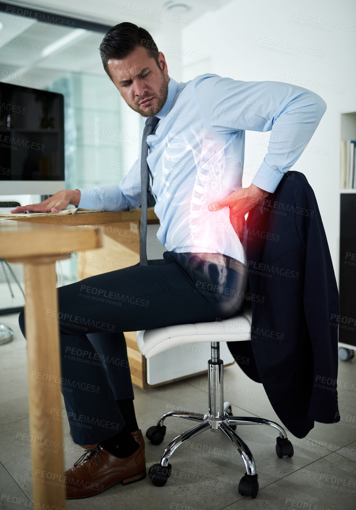 Buy stock photo Shot of a young businessman experiencing back pain highlighted in glowing red at work