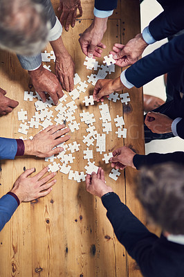 Buy stock photo High angle shot of a group of businesspeople building a puzzle together in an office