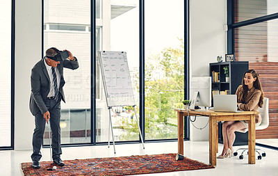 Buy stock photo Shot of a businesswoman watching her colleague play golf while wearing a VR headset in an office