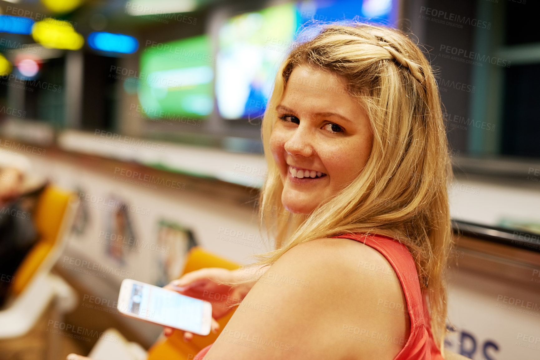 Buy stock photo Portrait of a young woman using a cellphone while sitting in an airport departure lounge