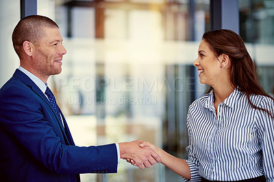 Buy stock photo Shot of two businesspeople shaking hands in an office