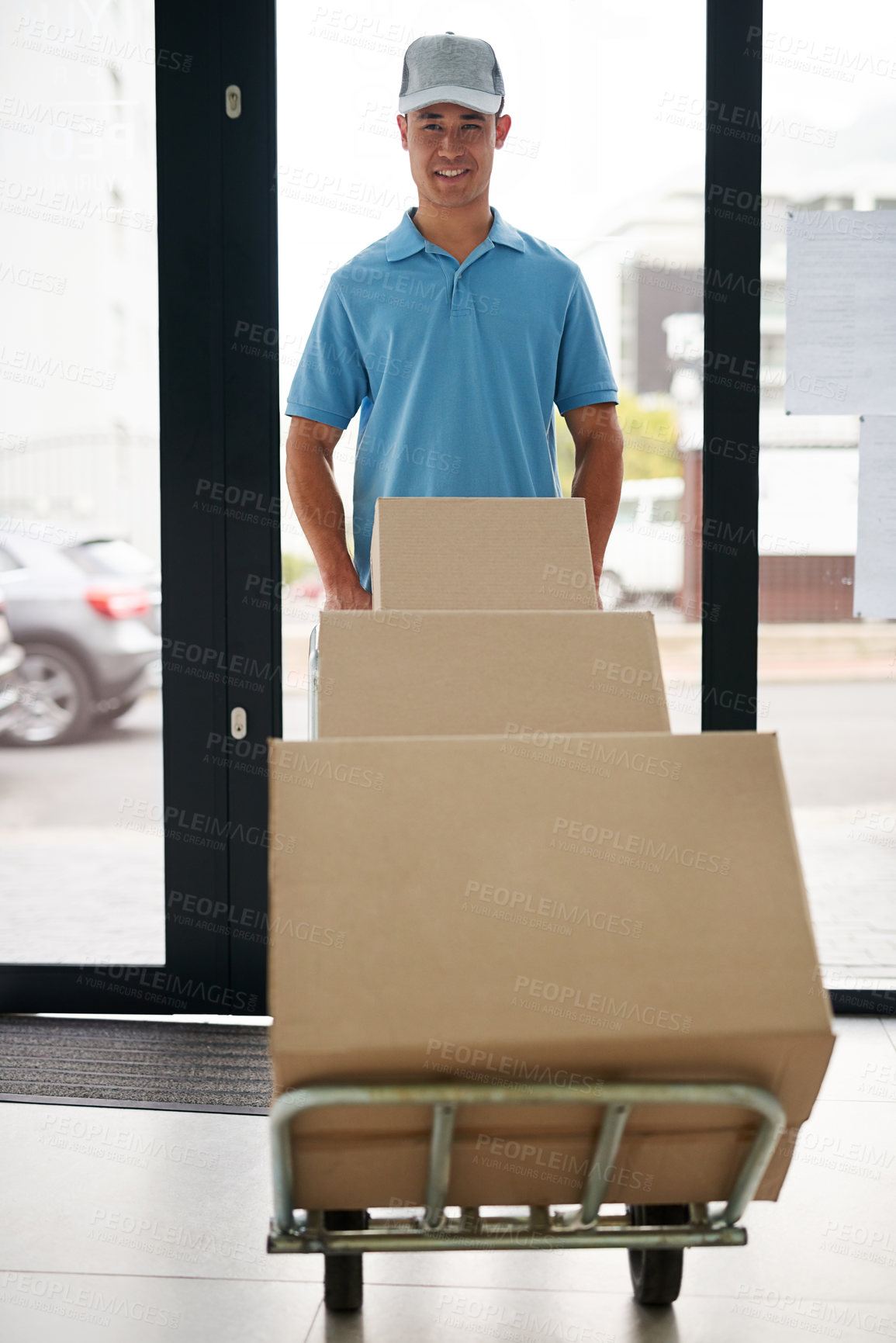 Buy stock photo Portrait of a courier pushing a trolley of boxes while making a delivery