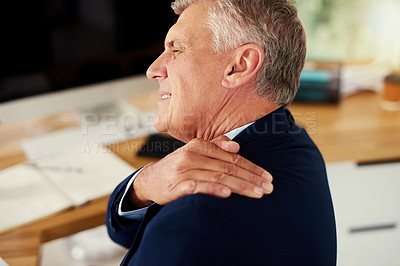 Buy stock photo Cropped shot of a mature businessman experiencing shoulder pain while working in an office