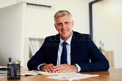Buy stock photo Portrait of a confident mature businessman sitting at his desk in an office