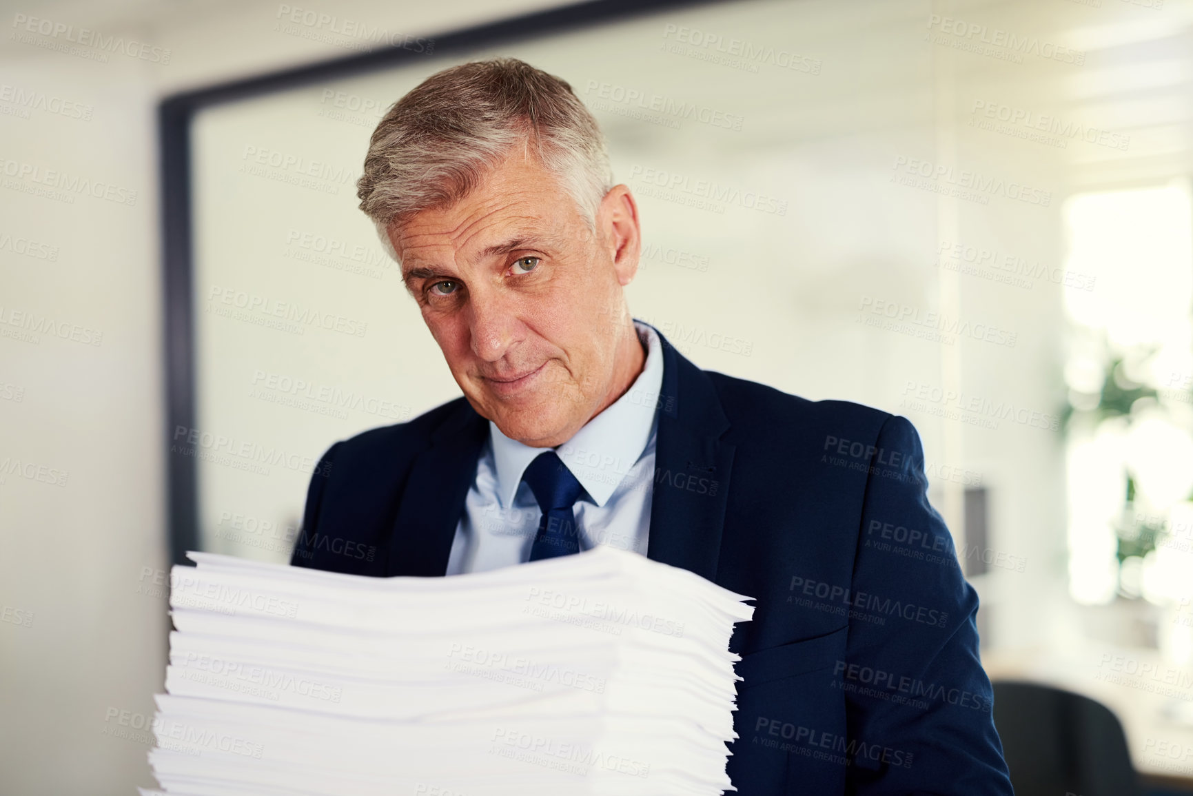 Buy stock photo Portrait of a mature businessman holding a pile of paperwork in an office