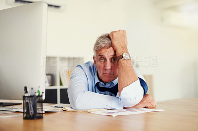 Buy stock photo Portrait of a mature businessman looking stressed out while sitting at his desk in an office