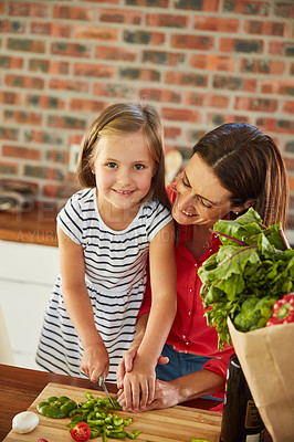 Buy stock photo Portrait of a cute little girl chopping vegetables in the kitchen with her mother