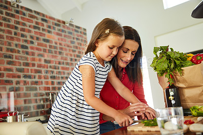 Buy stock photo Shot of a cute little girl chopping vegetables in the kitchen with her mother