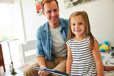 Buy stock photo Shot of a father and his young daughter sitting together in the living room at home using a digital tablet