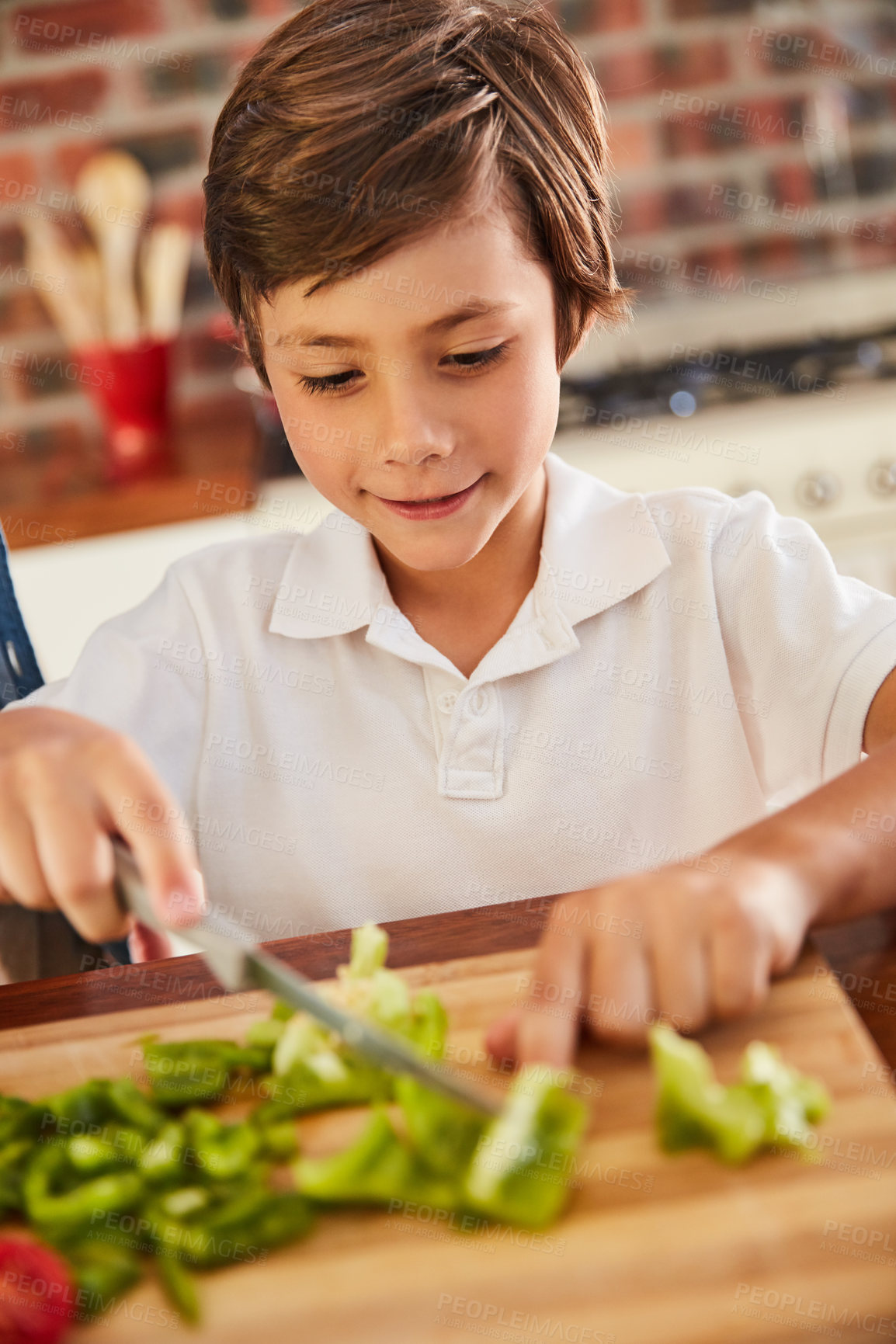 Buy stock photo Shot of an adorable little boy chopping vegetables on his own in the kitchen