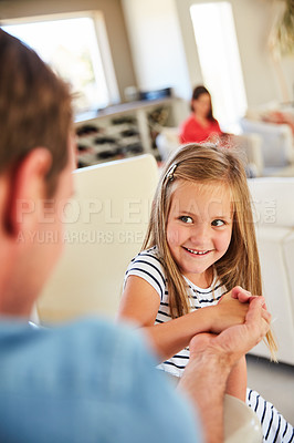 Buy stock photo Shot of a smiling littlegirl and her father arm wrestling together at home