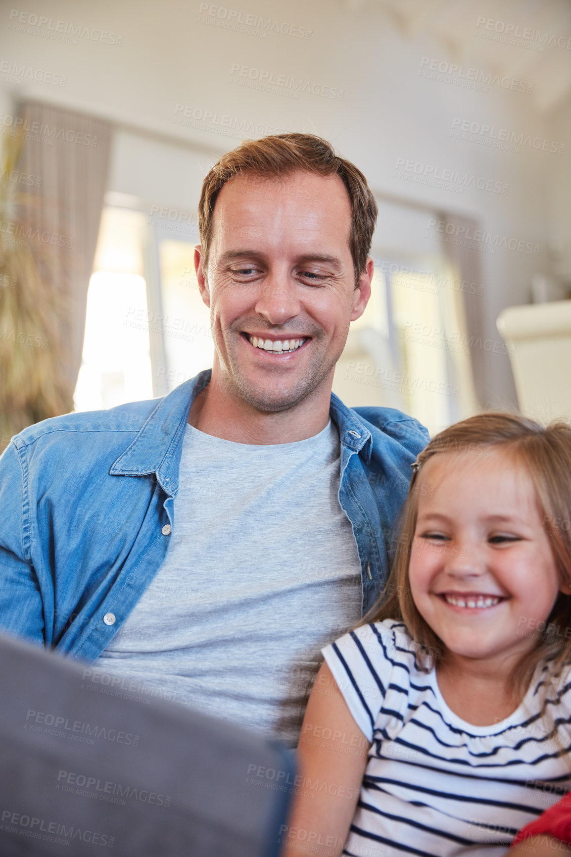 Buy stock photo Shot of a father and his young daughter sitting together in the living room at home using a digital tablet