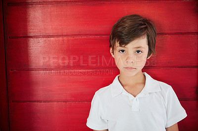 Buy stock photo Portrait of a sad little boy standing against a red wall