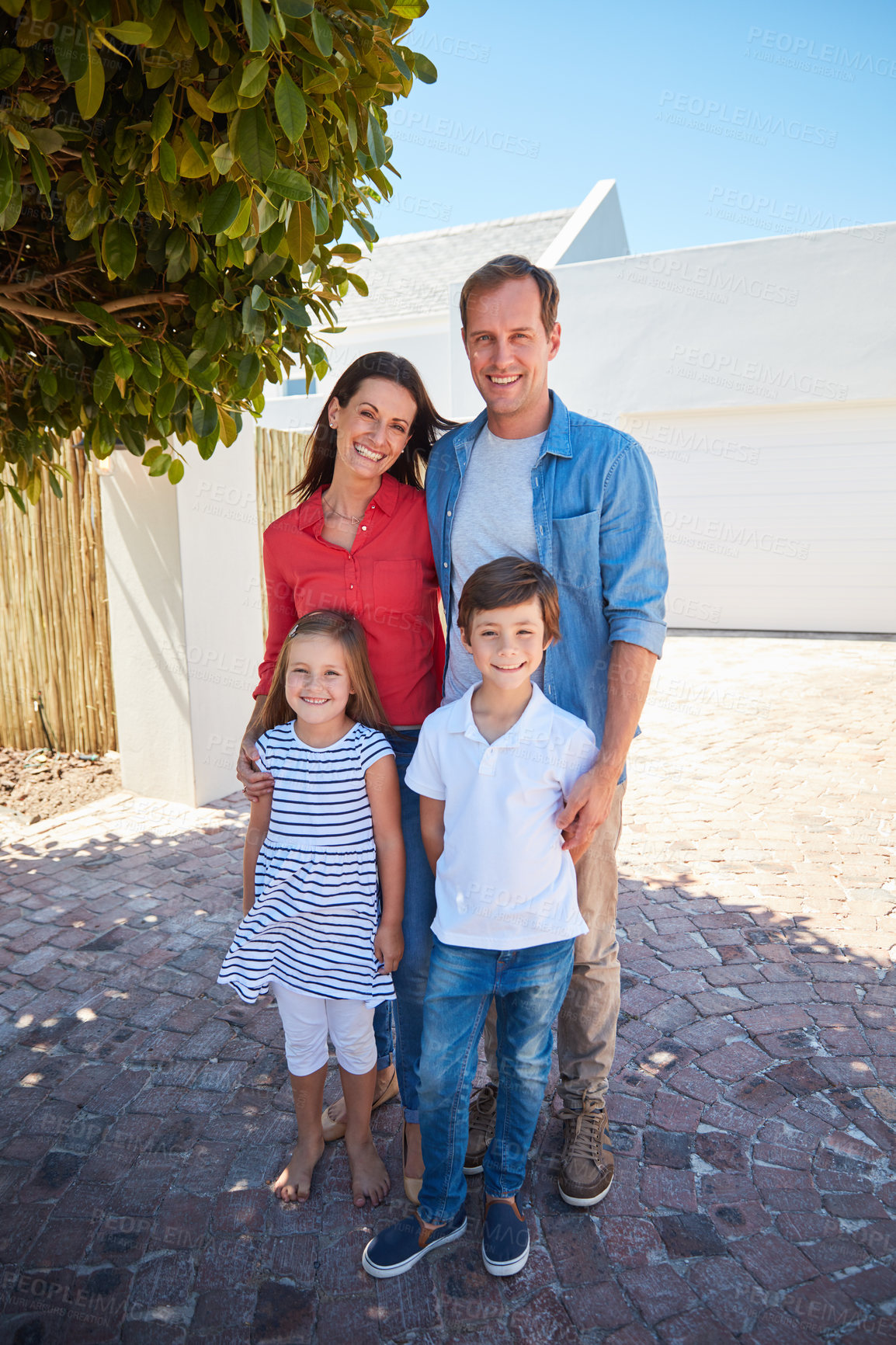 Buy stock photo Portrait of smiling parents and their young son and daughter standing outside in their yard on a sunny day