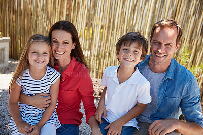 Buy stock photo Portrait of smiling parents and their young son and daughter sitting outside in their yard on a sunny day