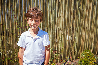 Buy stock photo Portrait of a smiling little boy standing outside on a sunny day